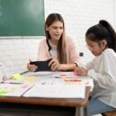 a classroom with a teacher and two students working on colorful educational activities