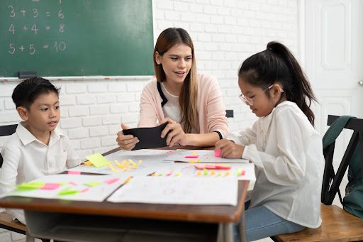 a classroom with a teacher and two students working on colorful educational activities