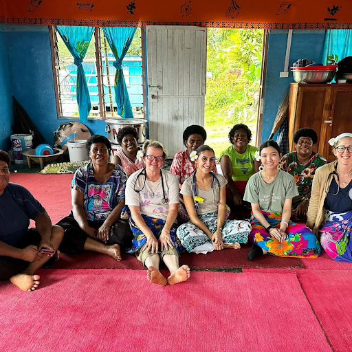 medical volunteers with stethoscopes pose for a picture with local Fijian women