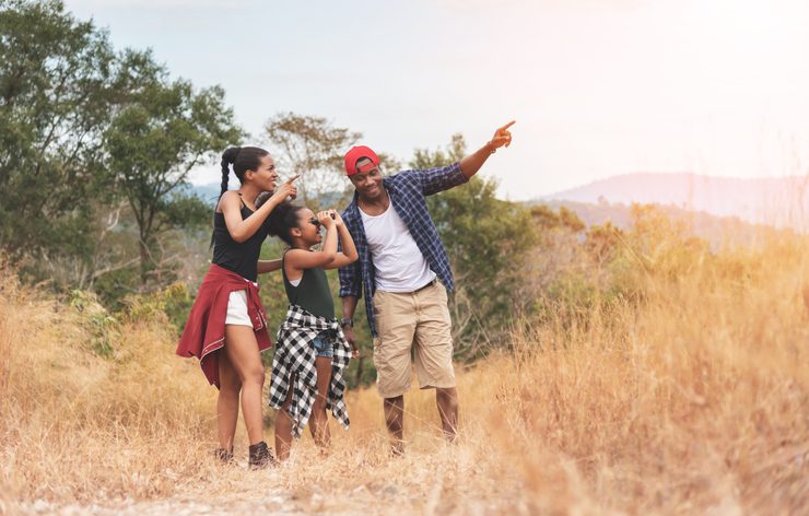 African-American Father, Mother and girl daughter using binocular while trekking on mountain at outside on holiday. VolunteerForever
